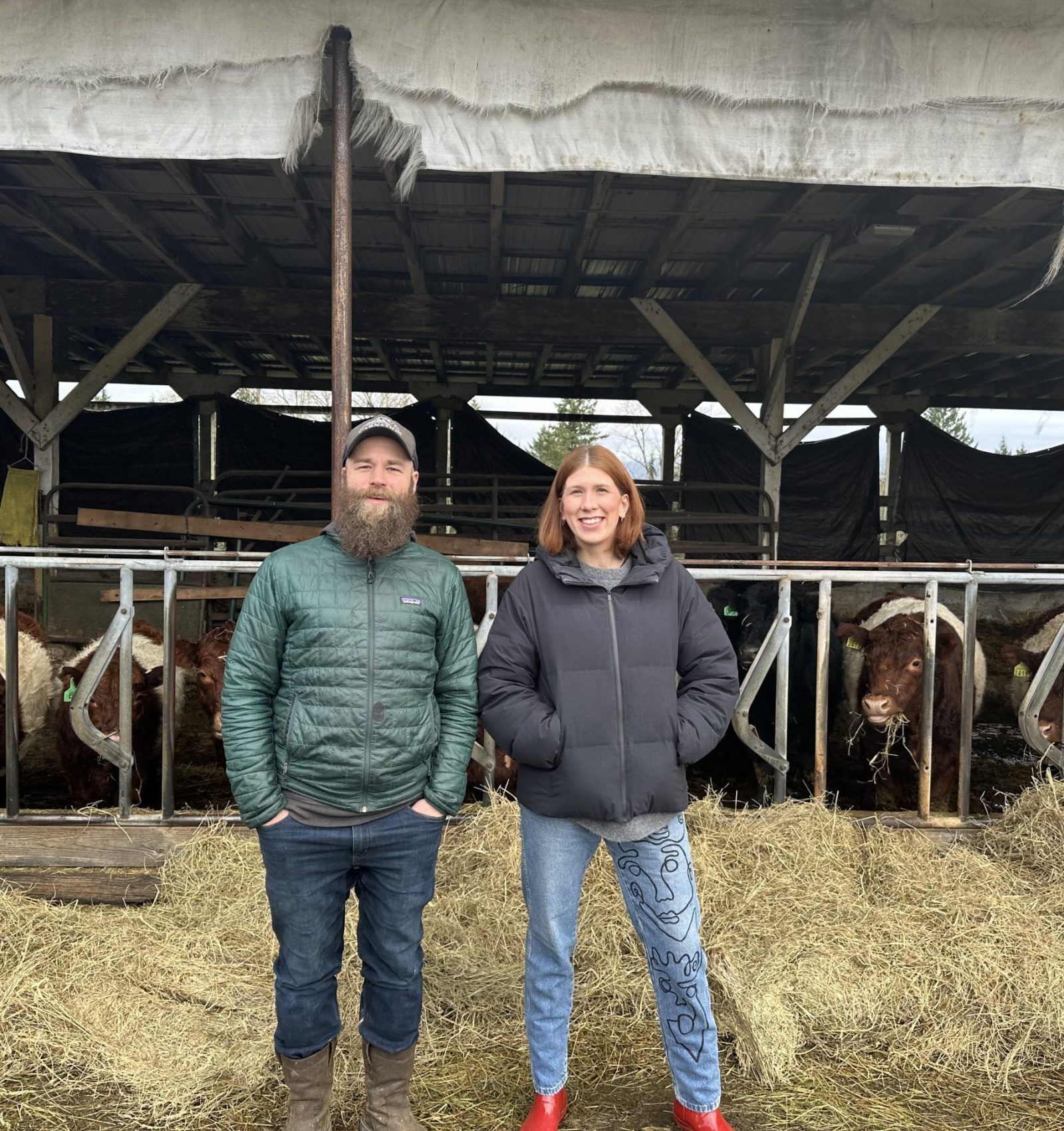 Chef Maty from Red Clog Kitchen in Woodinville smiling with Eric from Carnation Farms in front of their cattle